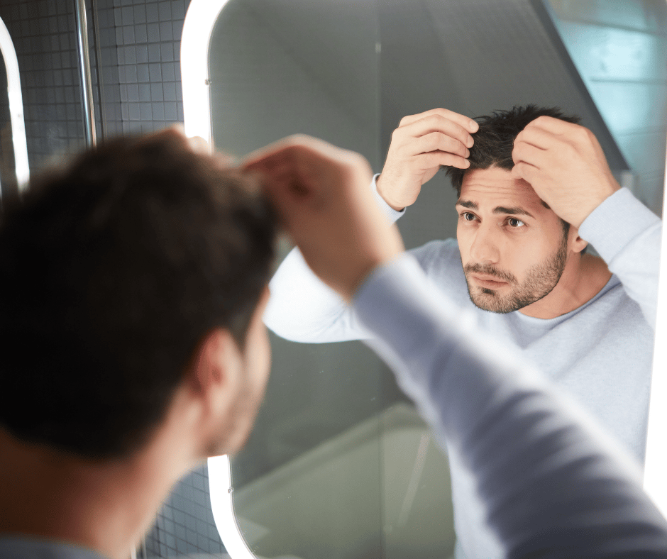 White man looking at his scalp in the mirror